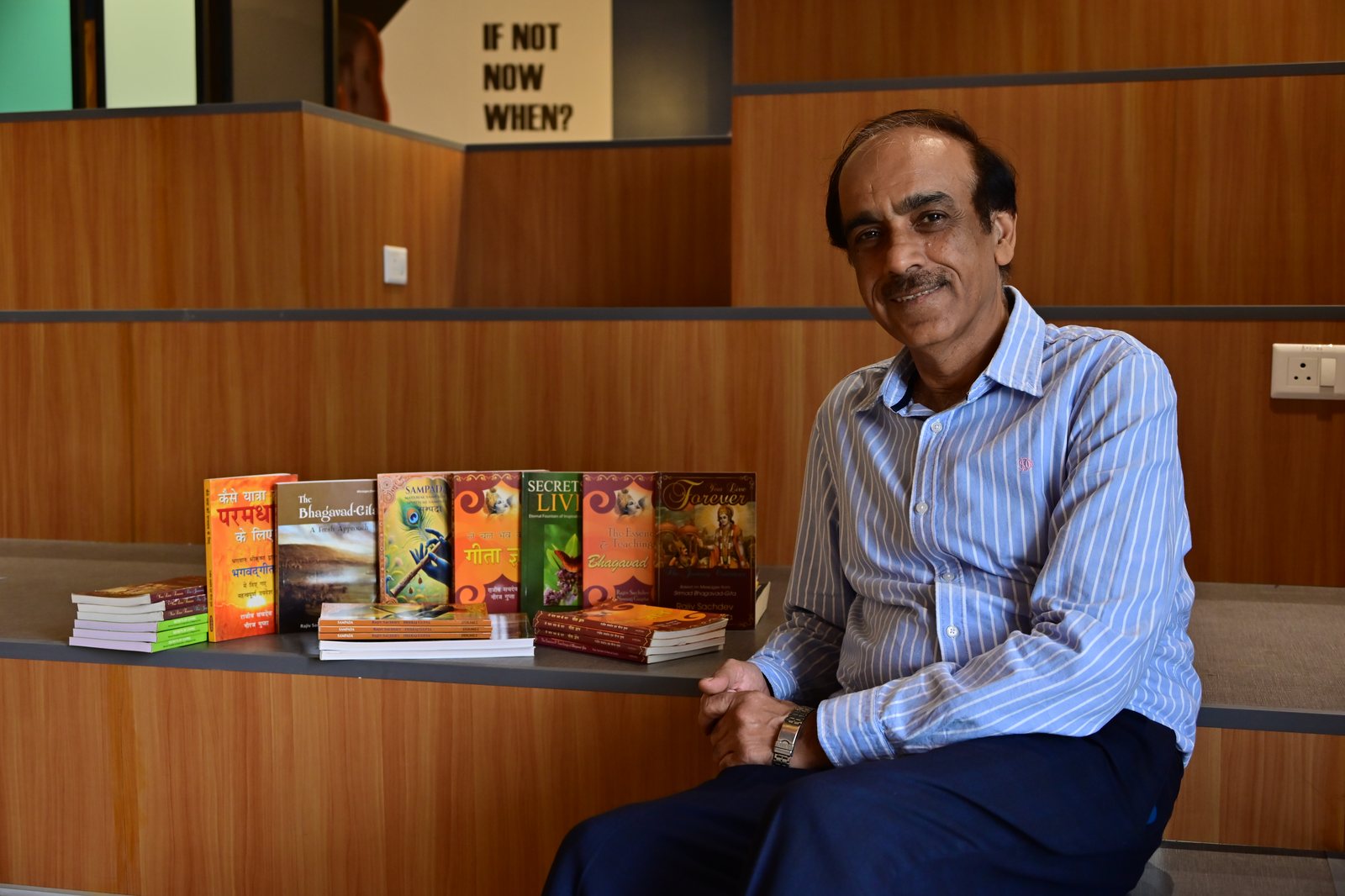 Rajiv Sachdev seated beside all seven of his published books